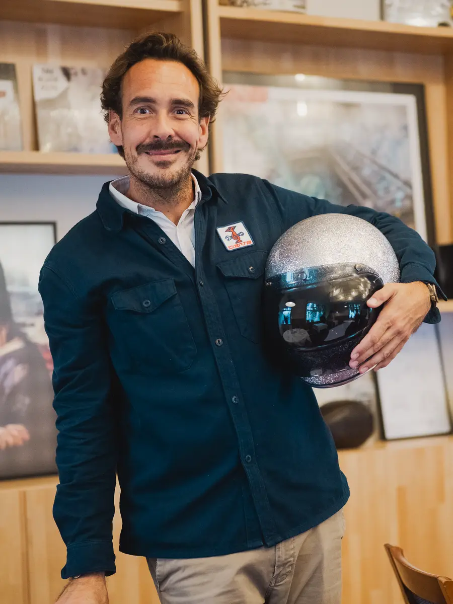 Romain, le gérant, une cloche sous le bras dans la salle du Pavillon