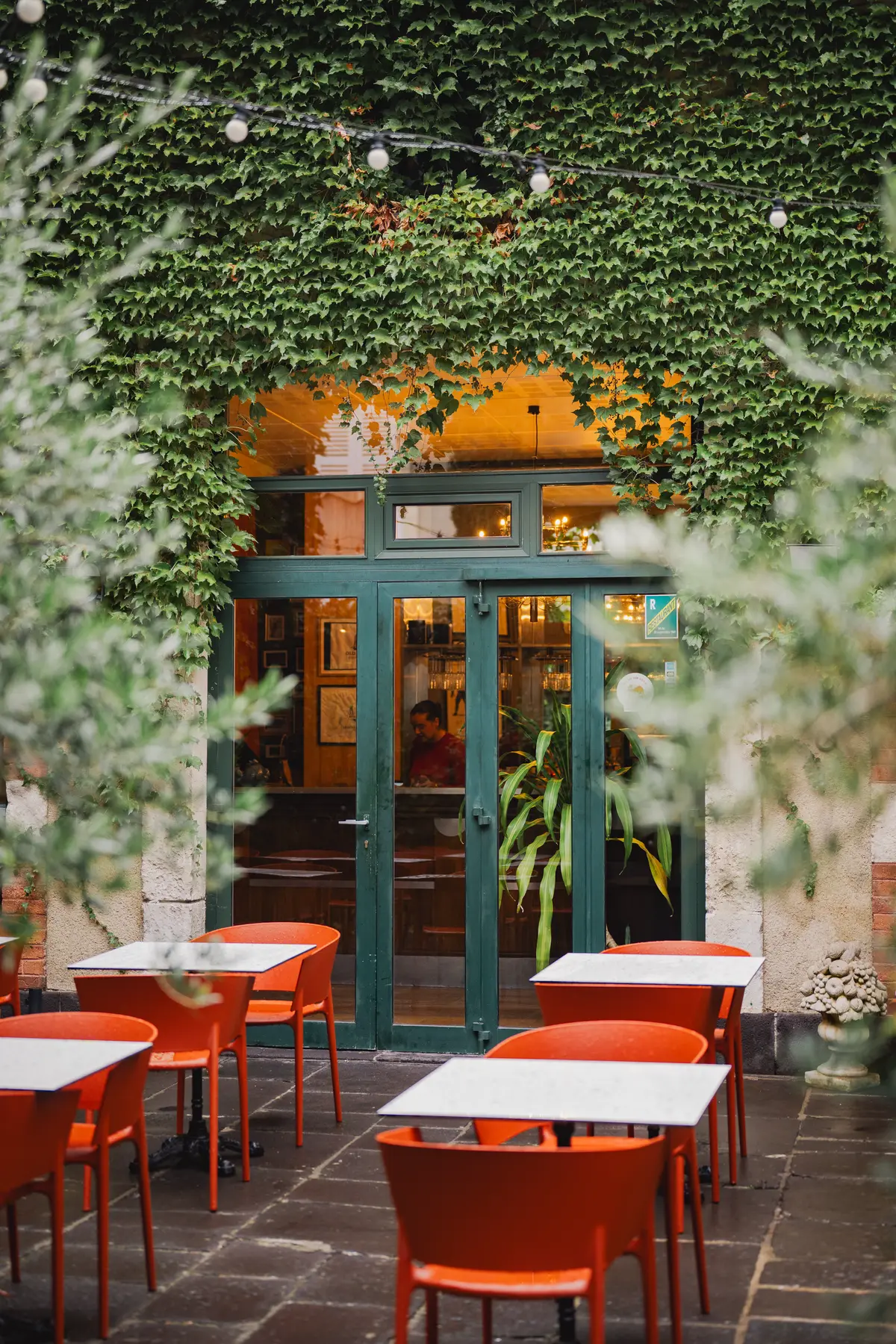 La cour du Pavillon, chaises orange sous le lierre