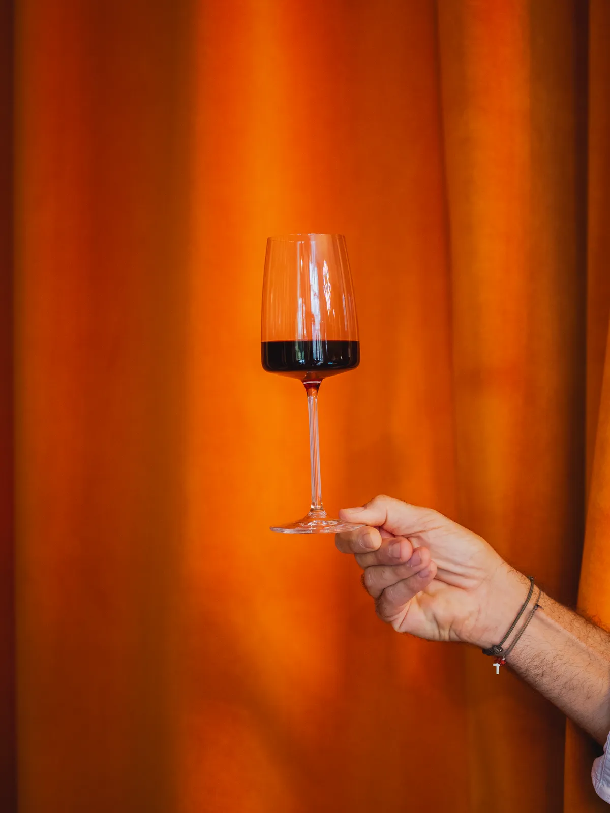 Un verre de vin rouge devant le rideau orange